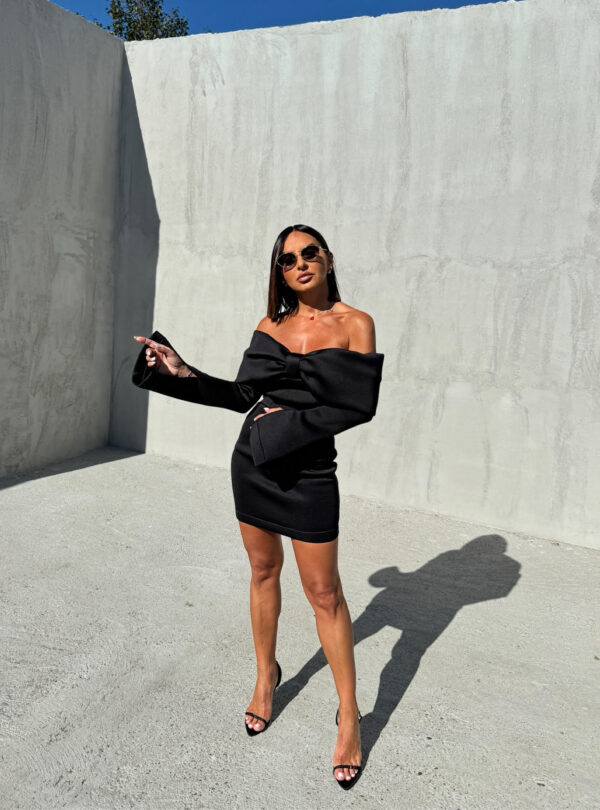 Mini crna elegantna haljina dugih rasečenih rukava, otkrivenih ramena i dekolteom u vidu mašne