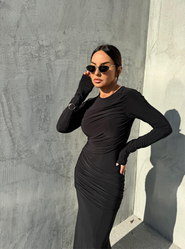 Duga uska elegantna crna haljina dugih rukava sa naborima preko grudi i bokova.