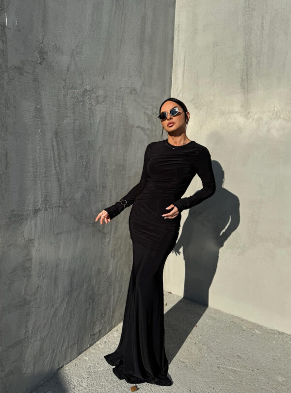 Duga uska elegantna crna haljina dugih rukava sa naborima preko grudi i bokova.