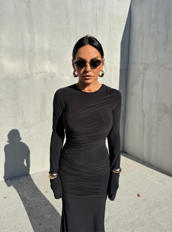 Duga uska elegantna crna haljina dugih rukava sa naborima preko grudi i bokova.