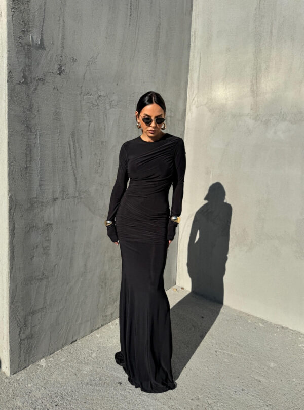Duga uska elegantna crna haljina dugih rukava sa naborima preko grudi i bokova.