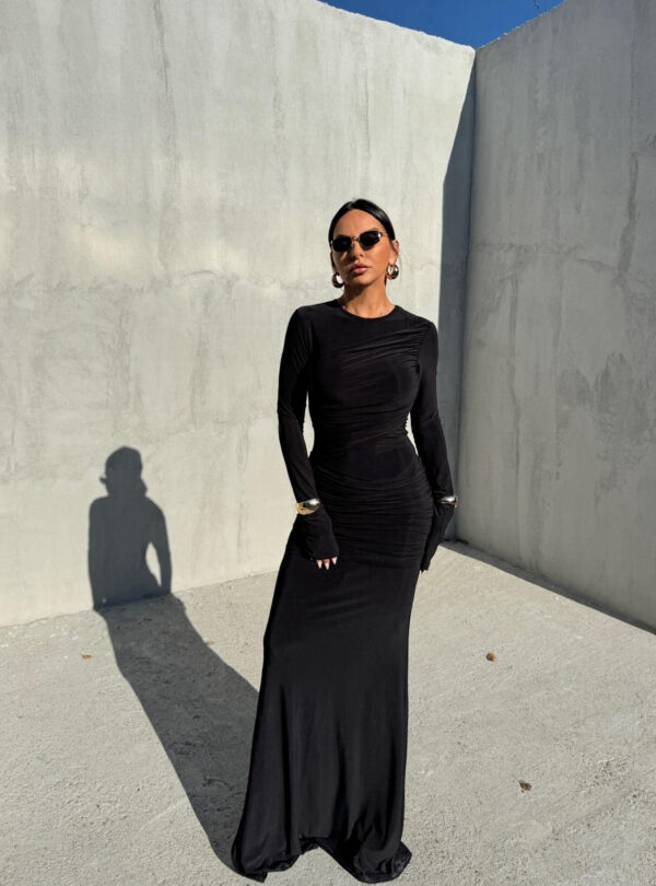 Duga uska elegantna crna haljina dugih rukava sa naborima preko grudi i bokova.