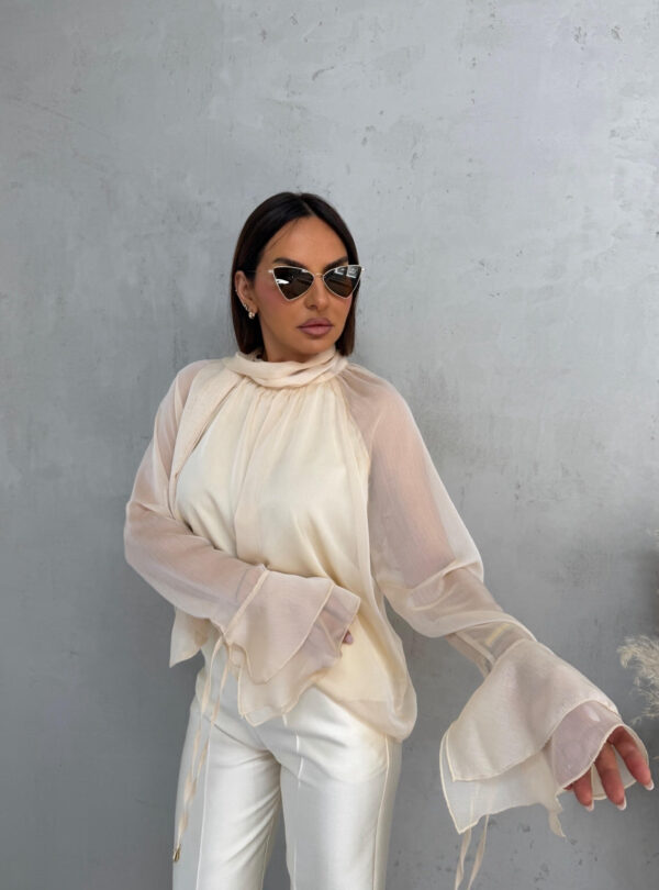 Bež lepršava polu-transparentna bluza sa karnerima na krajevima rukava i dekorativnim vezivanjem oko vrata