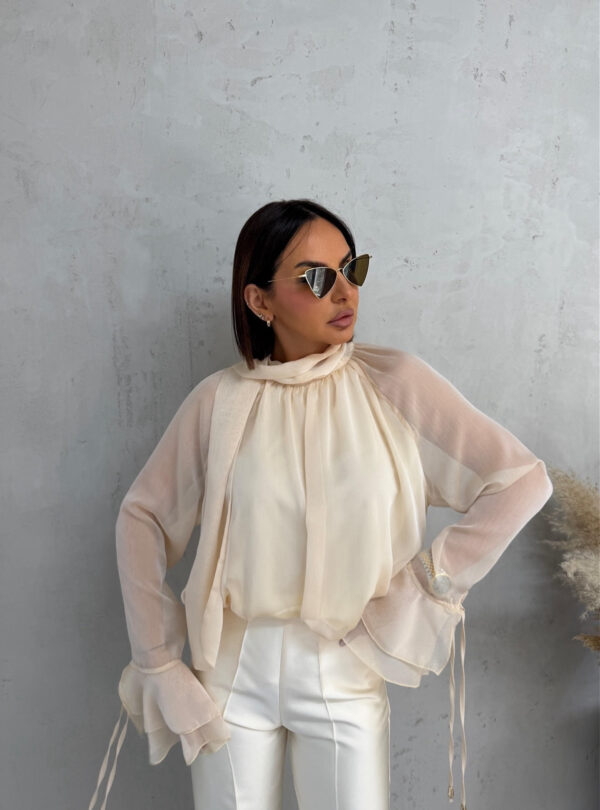 Bež lepršava polu-transparentna bluza sa karnerima na krajevima rukava i dekorativnim vezivanjem oko vrata