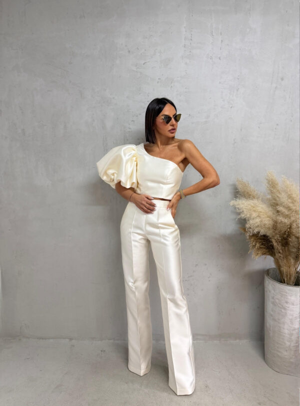 Bež sjajni komplet od čvrstog punijeg satena koji se sastoji od zvonastih pantalona visokog struka i kropovane asimetrične bluze sa predimenzioniranim rukavom