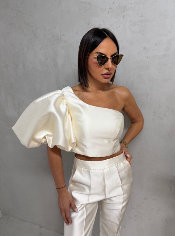 Bež sjajni komplet od čvrstog punijeg satena koji se sastoji od zvonastih pantalona visokog struka i kropovane asimetrične bluze sa predimenzioniranim rukavom