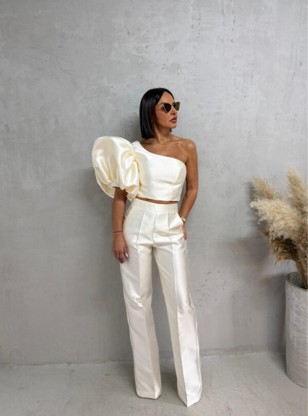 Bež sjajni komplet od čvrstog punijeg satena koji se sastoji od zvonastih pantalona visokog struka i kropovane asimetrične bluze sa predimenzioniranim rukavom