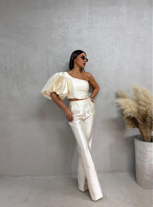 Bež sjajni komplet od čvrstog punijeg satena koji se sastoji od zvonastih pantalona visokog struka i kropovane asimetrične bluze sa predimenzioniranim rukavom